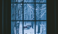 Forêt enneigée avec une vieille charrette rouge vue à travers une fenêtre – ambiance hivernale calme symbolisant le blues de l’hiver