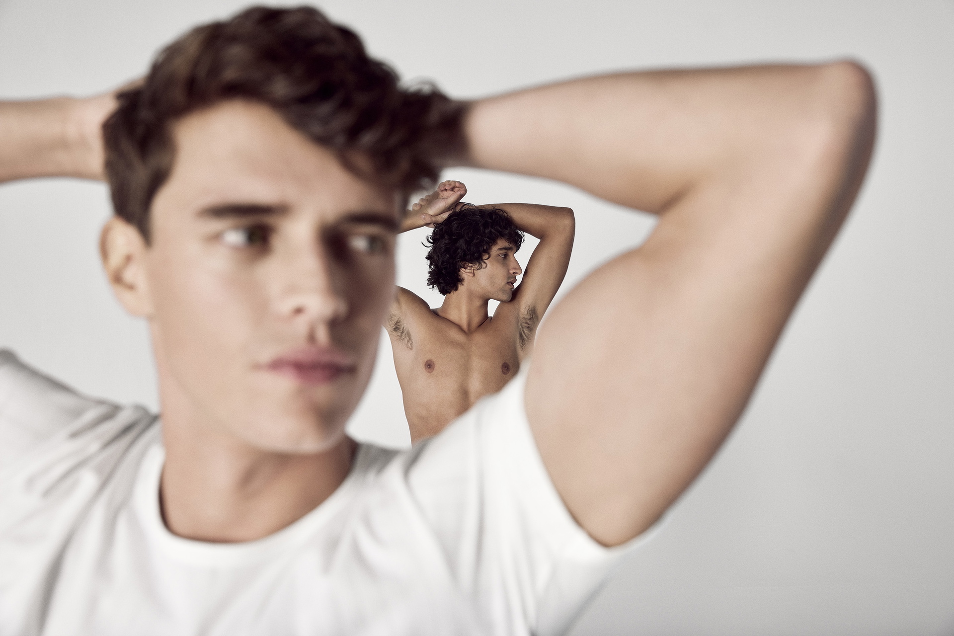 Two people with raised arms against a bright background; focus on the underarm area as a symbolic image for removing sweat stains