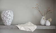 Scène de décoration minimaliste avec des vases blancs et du tissu sur une étagère grise ; une Culotte Midi Seamless CALIDA de la série Natural Skin placée au premier plan