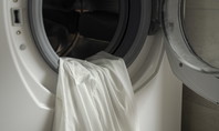 Offene Waschmaschine. In der Trommel liegt ein weisses Oberteil.