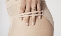 La donna indossa gli slip perizoma CALIDA ECO SENSE e tiene 4 dita attraverso il perizoma sui fianchi.
