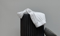 The picture shows a white item of clothing draped over a black, cylindrical object. Next to it are two grey, bowl-shaped objects stacked on top of each other.