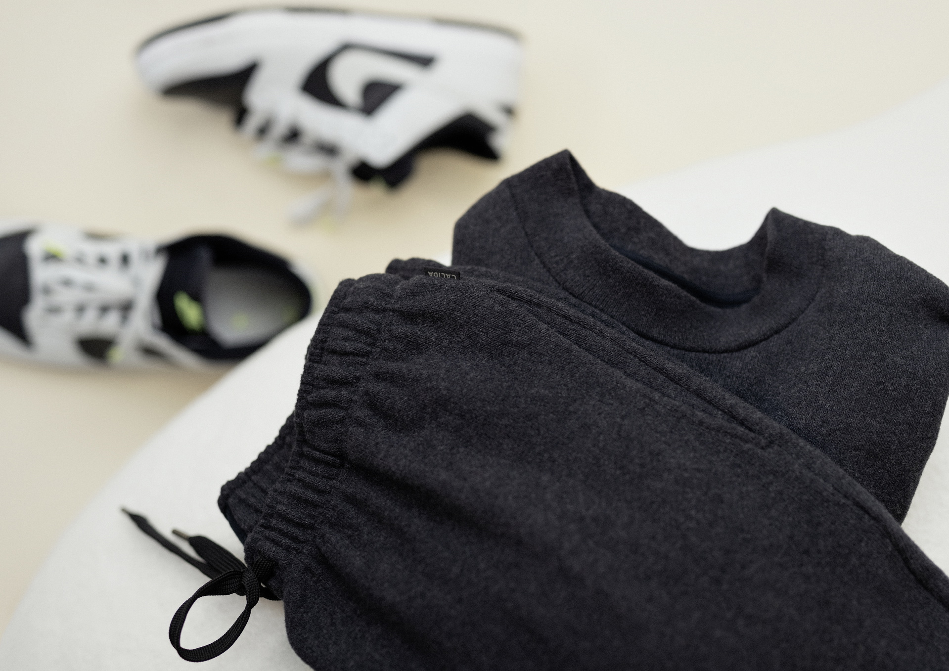 CALIDA RMX LOUNGE TIME OFF sweatshirt lying on a white couch. White sneakers can be seen in the background.