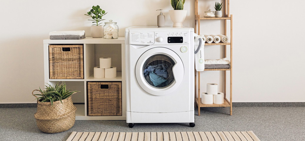 L'image montre une petite section d'une salle de bain. Deux étagères, une machine à laver et des serviettes soigneusement pliées peuvent être vues.
