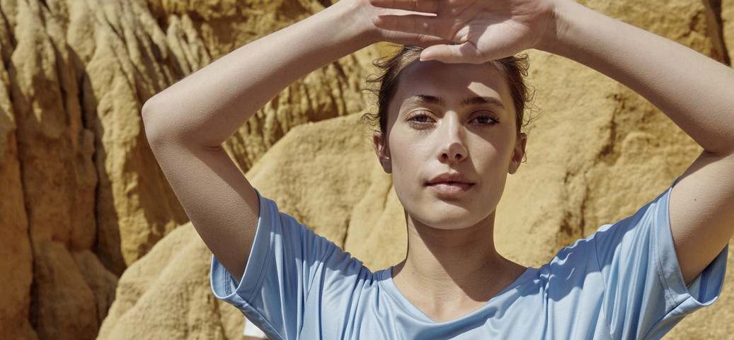 Une femme porte un t-shirt bleu de CALIDA et lève les bras.