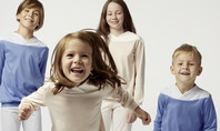 Vier Kinder in altersgerechten Schlafanzügen, die fröhlich in die Kamera schauen, symbolisieren den Schlafbedarf bei Kindern und die Bedeutung von bequemer Nachtkleidung für erholsamen Schlaf