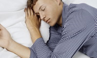 Ein Mann liegt wach im Bett mit geschlossenen Augen, passend zur Frage: Warum kann ich nicht schlafen, obwohl ich müde bin?