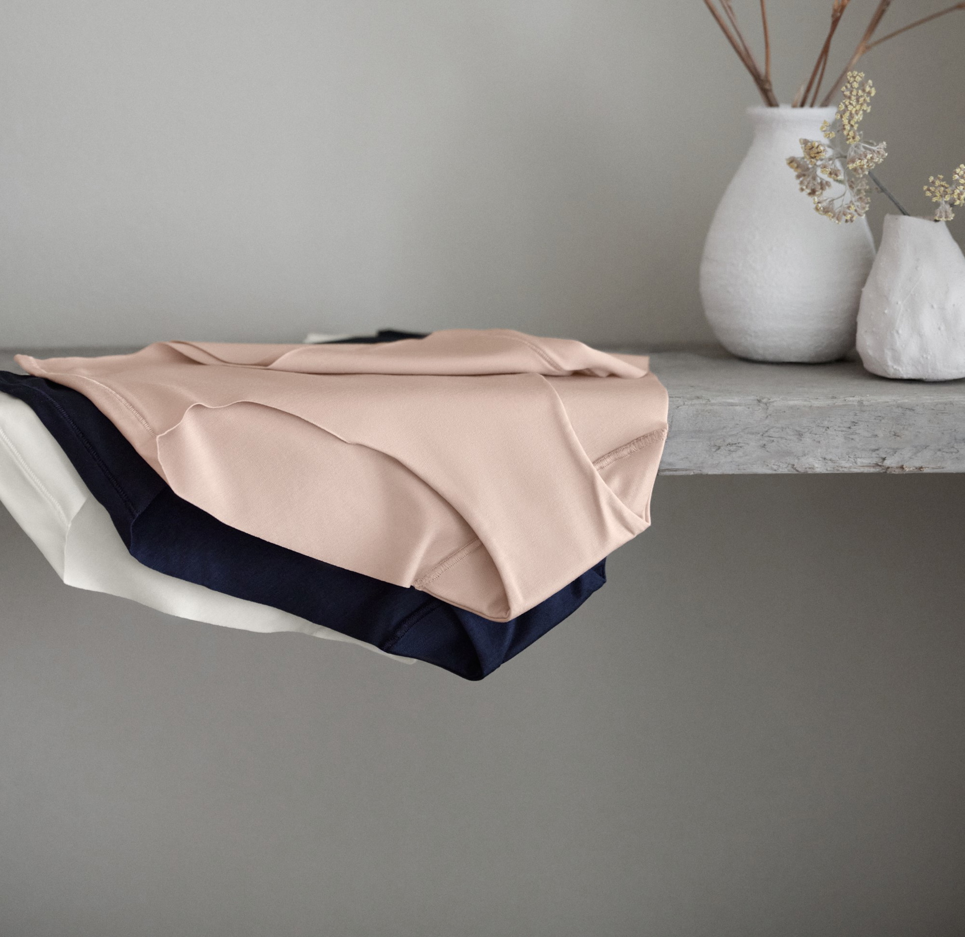 On y voit trois pantys de CALIDA de la série Natural Skin dans différentes couleurs, bien rangés sur une étagère.