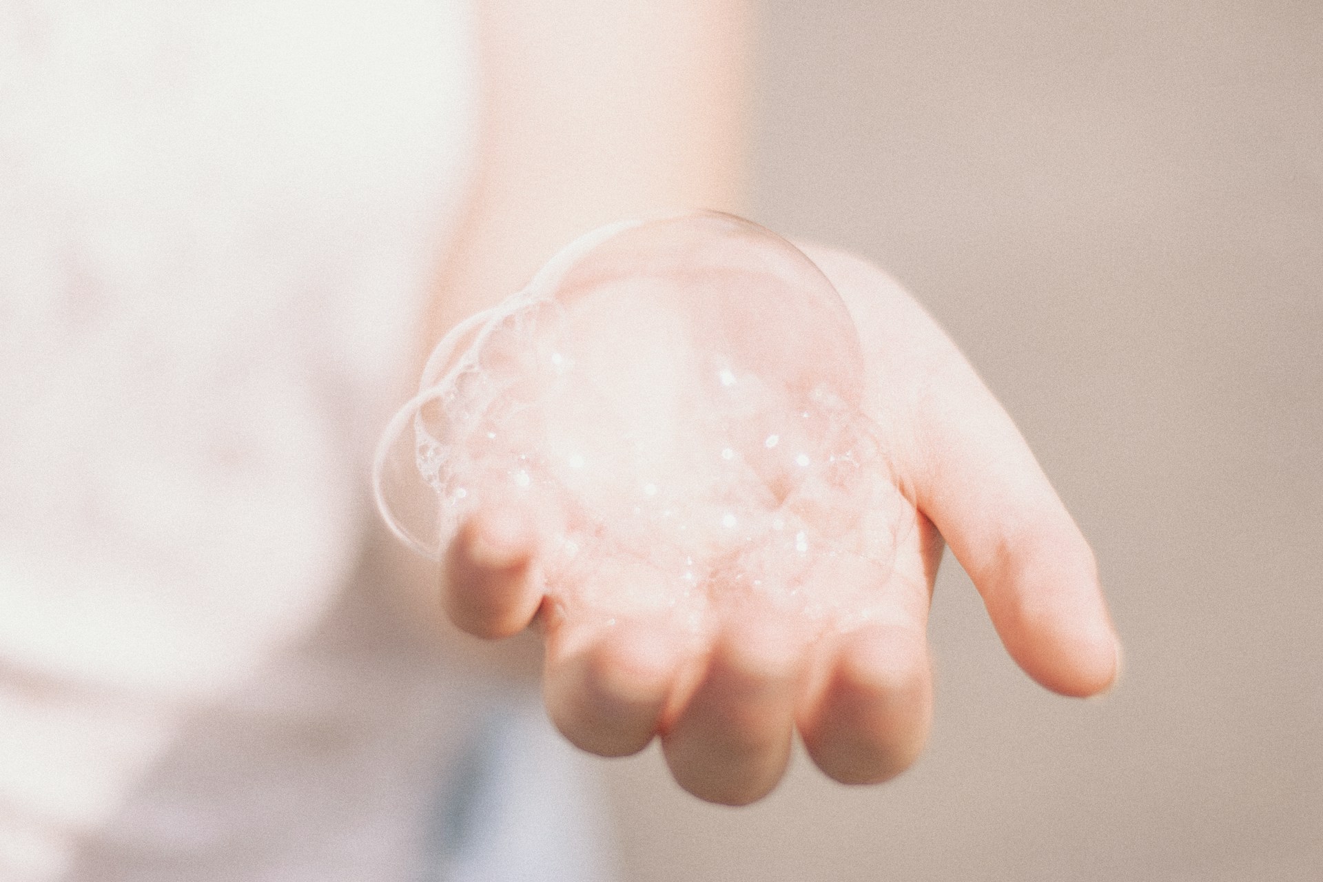 Main avec bulles de savon symbolisant le lavage doux à la main des vêtements, idéal pour les tissus délicats.