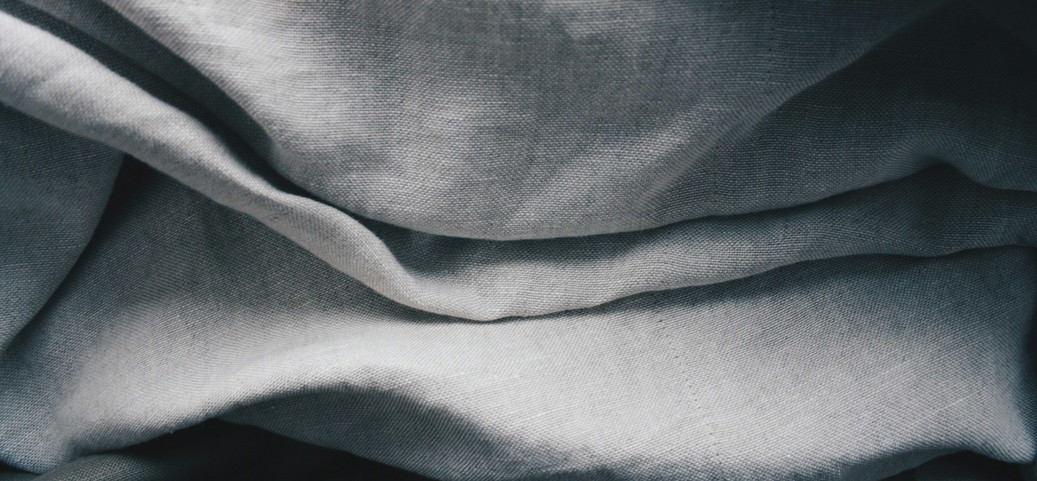 Détail de tissu de lin plié dans différentes nuances de gris.