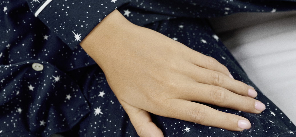 Gros plan d'une main sur un pyjama bleu foncé avec des motifs d'étoiles blanches.