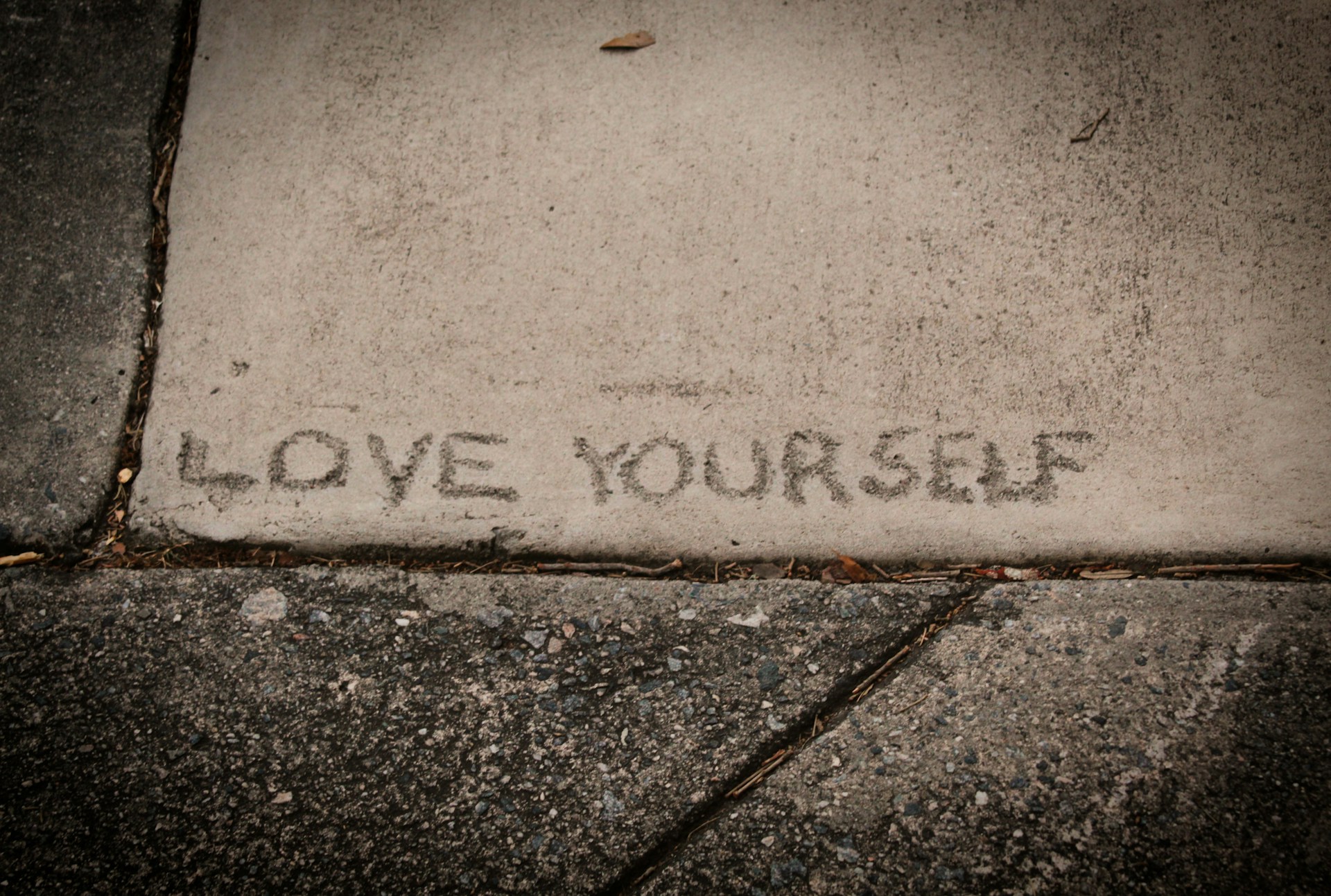The words ‘LOVE YOURSELF’ engraved in the concrete - learn to love yourself and value yourself.