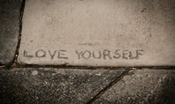 The words ‘LOVE YOURSELF’ engraved in the concrete - learn to love yourself and value yourself.