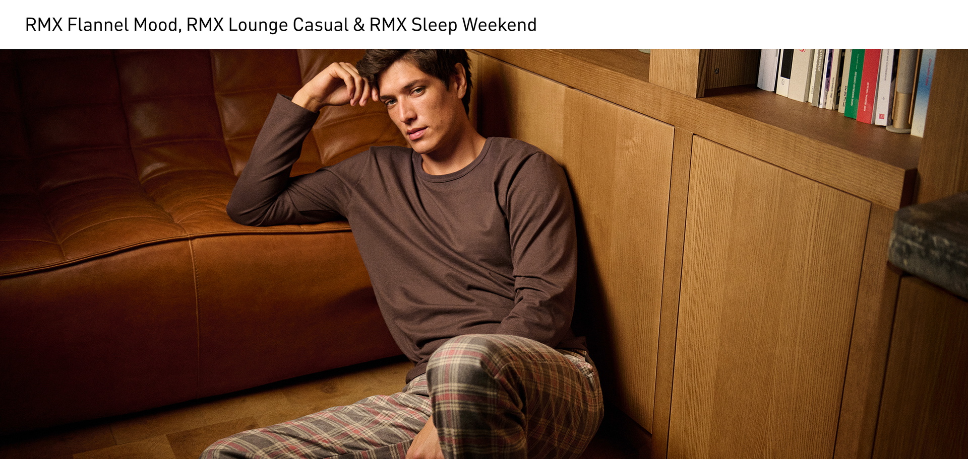 The model is sitting relaxed on the floor, wearing a brown long-sleeved shirt from the RMX Sleep Weekend series, paired with checked pyjama trousers with side pockets from the RMX Flannel Mood series.