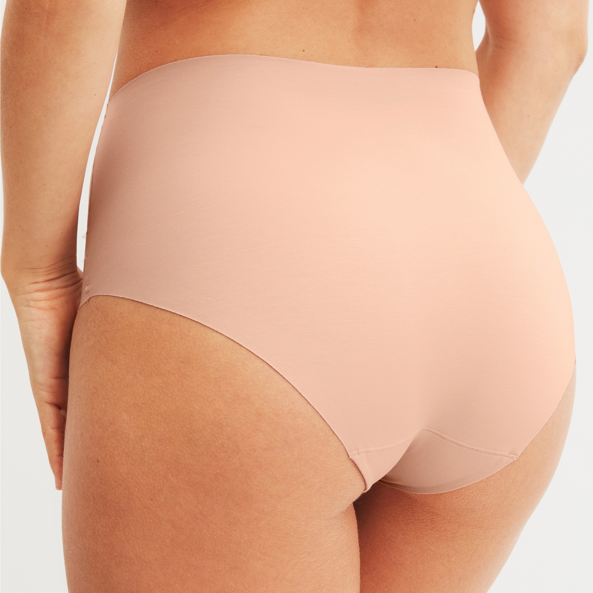 Woman wearing high-waist brief in nude with a high waistband and seamless design - back view
