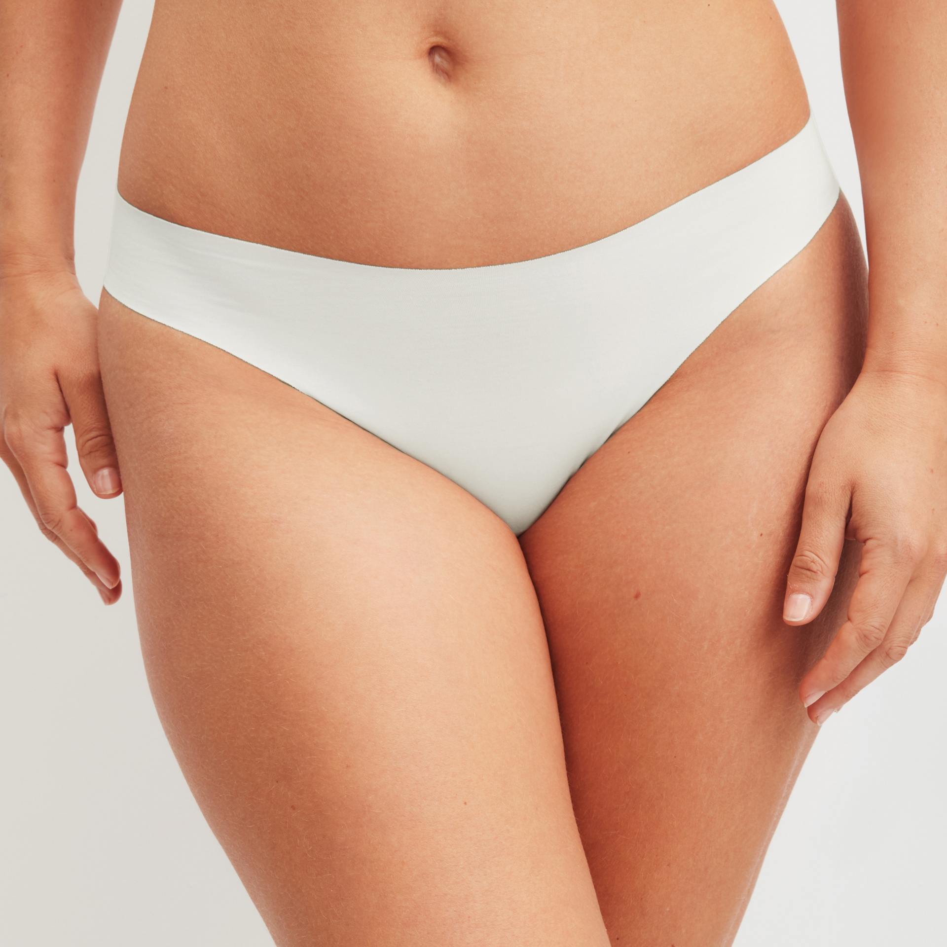 Woman wears seamless, white panties with a smooth surface – front view with invisible finish for tight clothing.