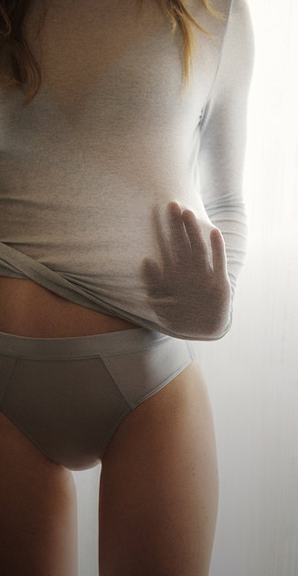 Close-up of a light grey long-sleeve made of soft material, worn on the body and focusing on the snug, form-fitting fit.