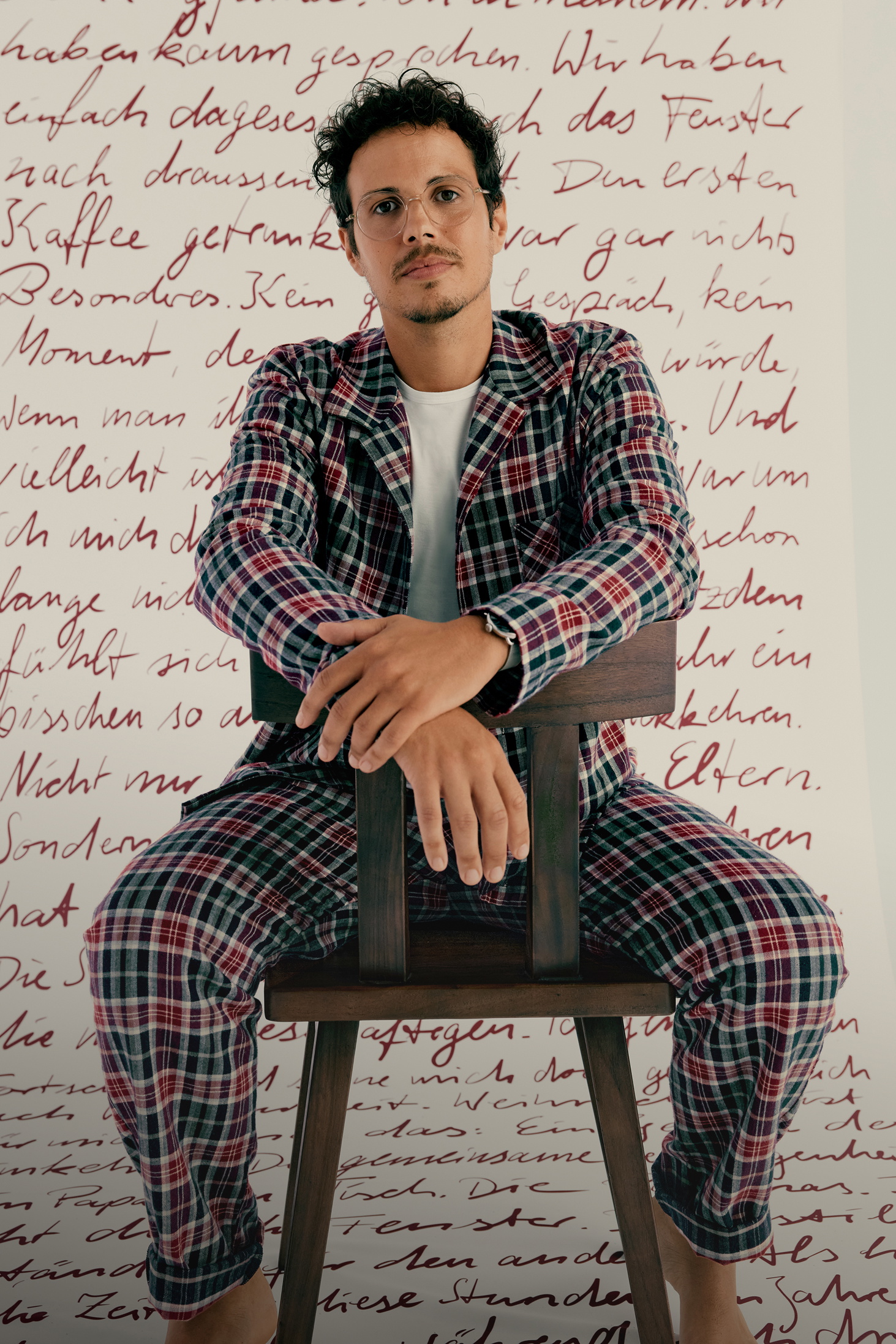 Man in Christmas plaid flannel pajamas in front of a scroll with Christmas memories from CALIDA customers.