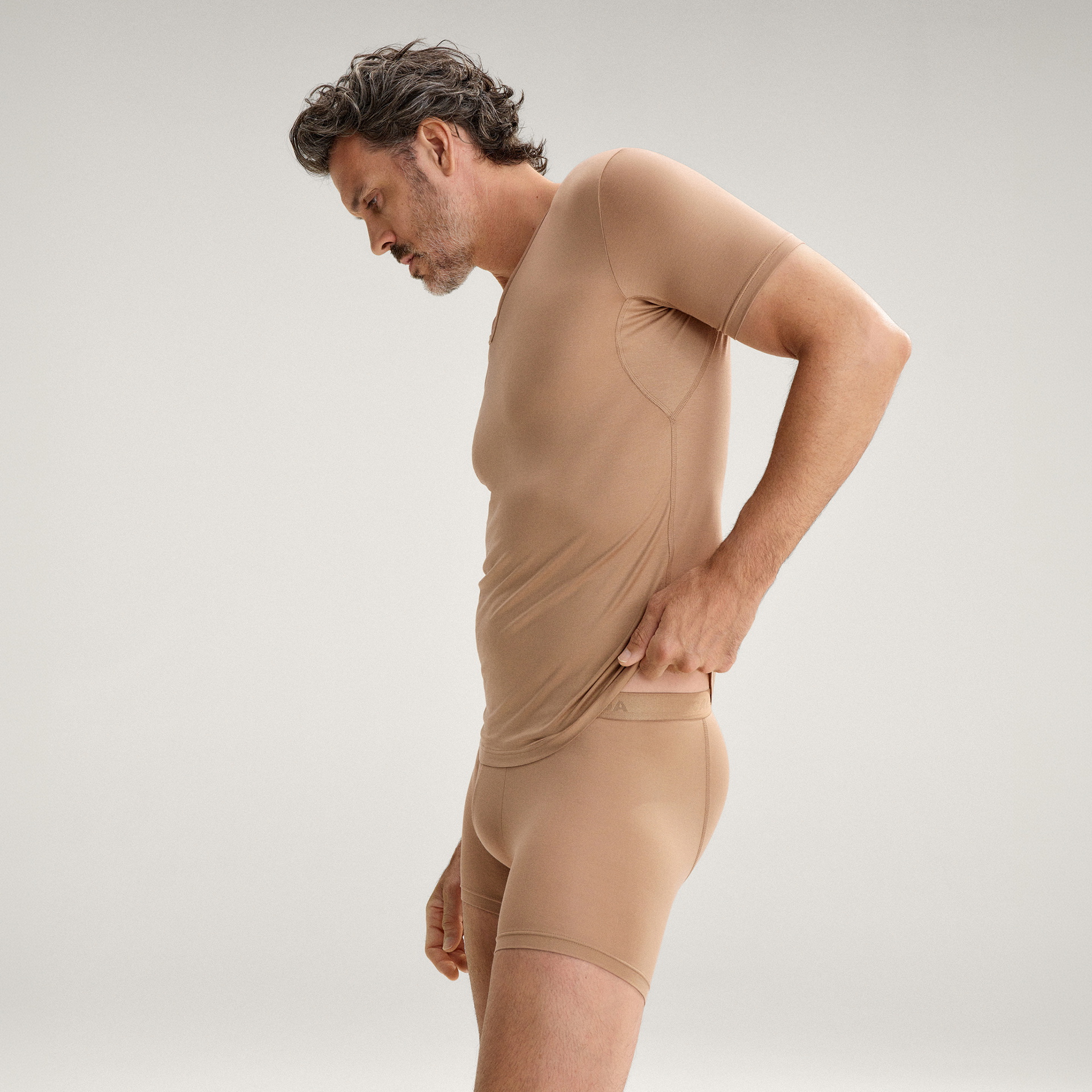Le mannequin porte un t-shirt beige de la série Natural Cooling de la marque CALIDA. 