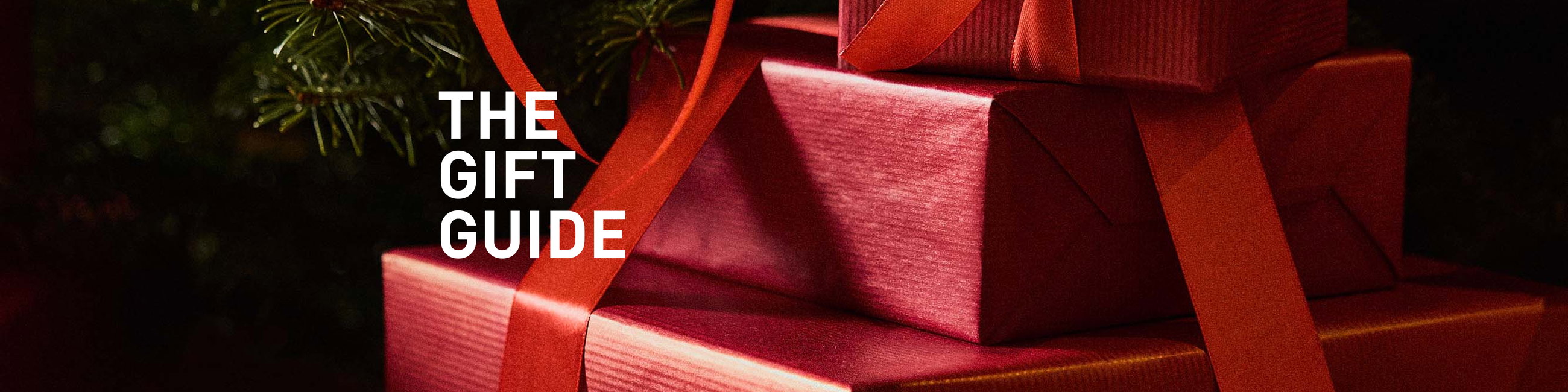 Des boîtes cadeaux emballées de façon festive en rouge vif, mises en scène comme une entrée atmosphérique dans le Guide Cadeaux CALIDA.