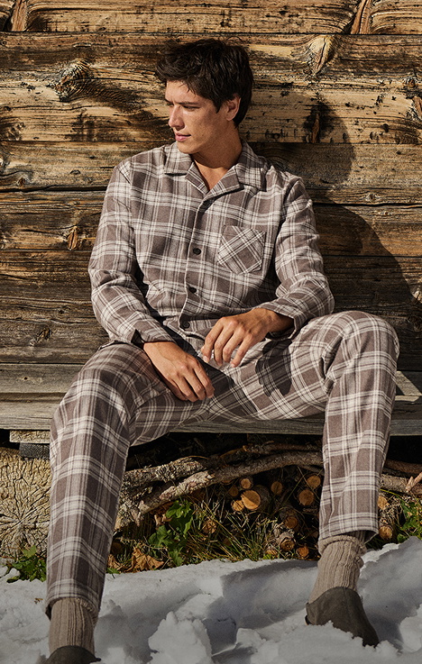 La modella si rilassa in un accogliente chalet di montagna e indossa il pigiama con bottoni della serie Relax Flannel Mood, abbinato alle calze coordinate per un look all’insegna del comfort.